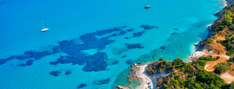 Segeltörn in den Bahamas - Segelboote auf dem türkisblauen Wasser umgeben von üppiger Natur