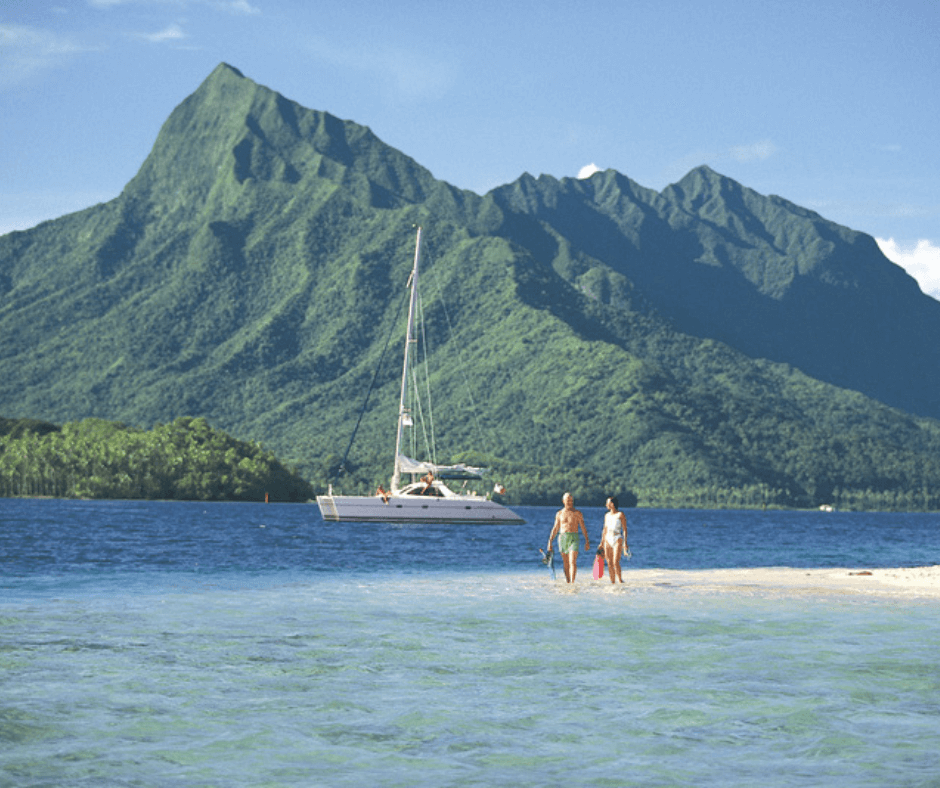 Mann und Frau am Strand mit Boot und Berglandschaft im Hintergrund 