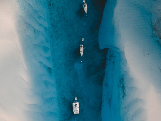 Katamarane und Segelboote inmitten von türkisblauem Wasser und weißem Sand auf den Bahamas