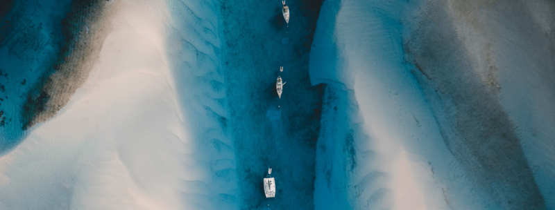 Katamarane und Segelboote inmitten von türkisblauem Wasser und weißem Sand auf den Bahamas