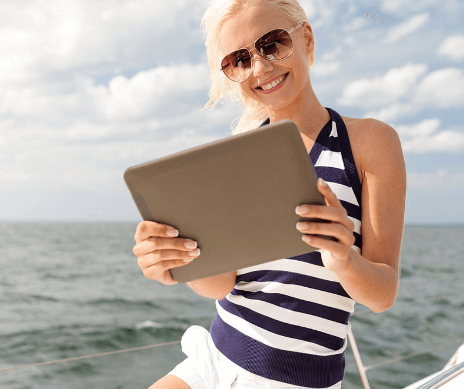 Frau, die ein Tablet auf einem Boot benutzt 