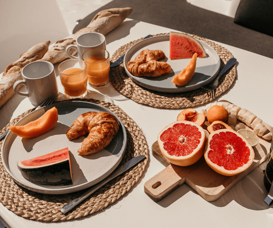 Frühstück an Bord mit Grapefruit, Melone, Croissants, Saft und Kaffee
