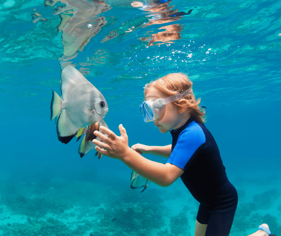 Kind beim Schnorcheln auf den Malediven, Unterwasserblick mit  Fische