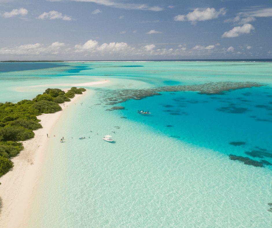 Segeln auf den Malediven, Boote auf dem türkisblauen Meer am angrenzenden weißen Sandstrand, grüne Insel