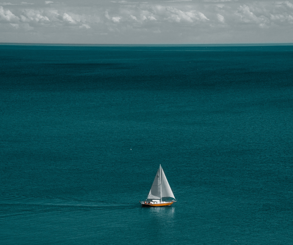 Ein Segelboot auf Reisen im strahlend blauem Wasser und bei bewölktem Wetter