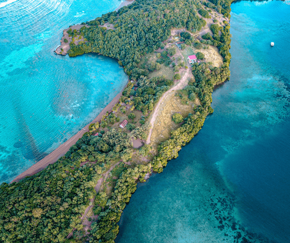 Vogelperspektive auf Grün bewachsene karibische Inseln inmitten azurblauem Wasser beim Segeltörn Martinique