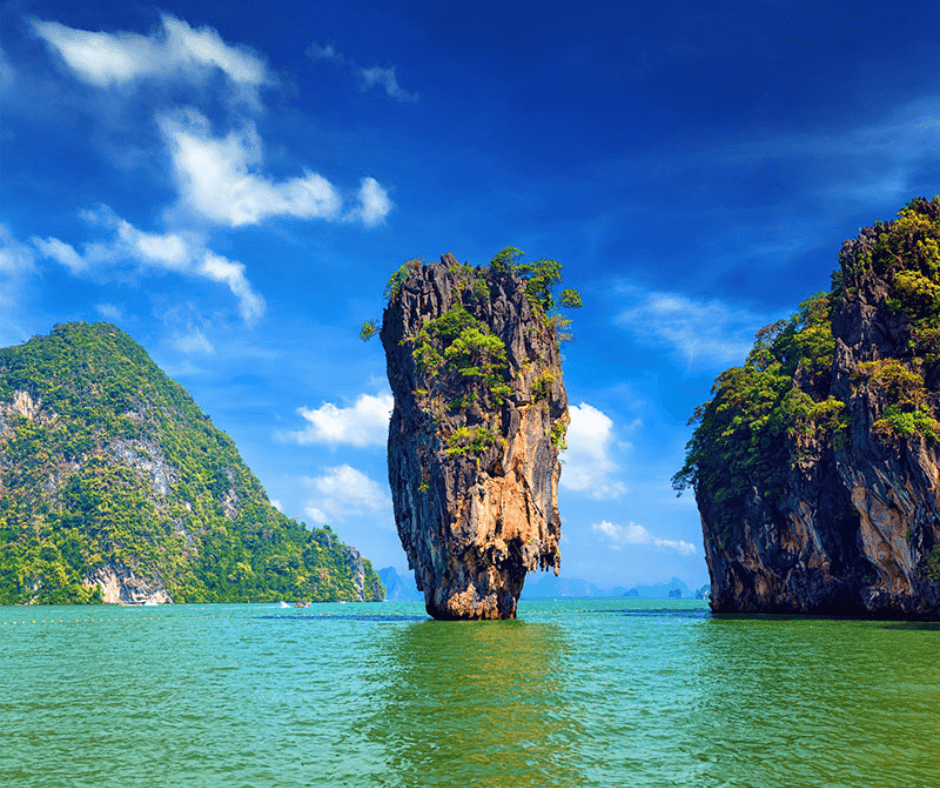 Ko Daeng Yai, Thailand - Bewachsene Felsen ragen aus dem smaragdgrünen Wasser