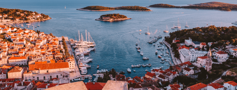 Inselhopping Kroatien - Hvar aus der Vogelperspektive, Boote am Hafen, Sonnenuntergang, historische Altstadt, üppige Inseln ragen aus dem Wasser