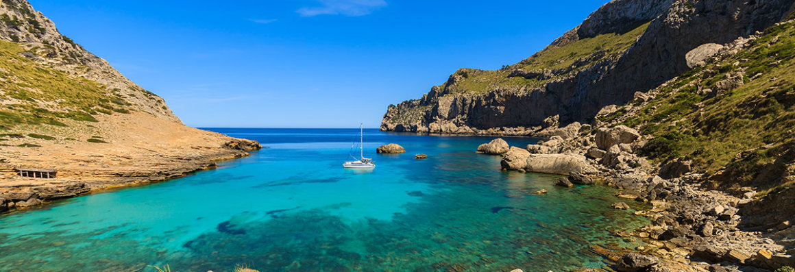 Segeltörn Mallorca, Balearen - Katamaran auf dem türkisblauen Wasser inmitten von Berglandschaft
