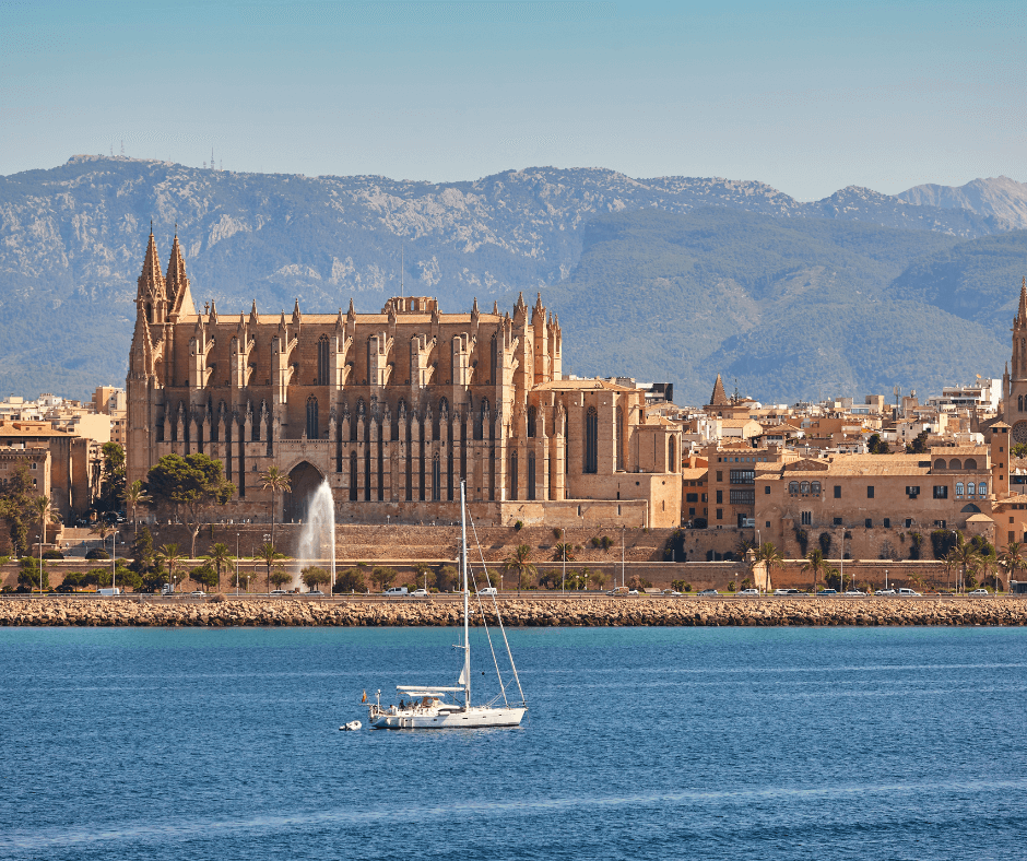 Segeltörn Mallorca, Segelboot auf dem Wasser mit der Kathedrale und Berge im Hintergrund