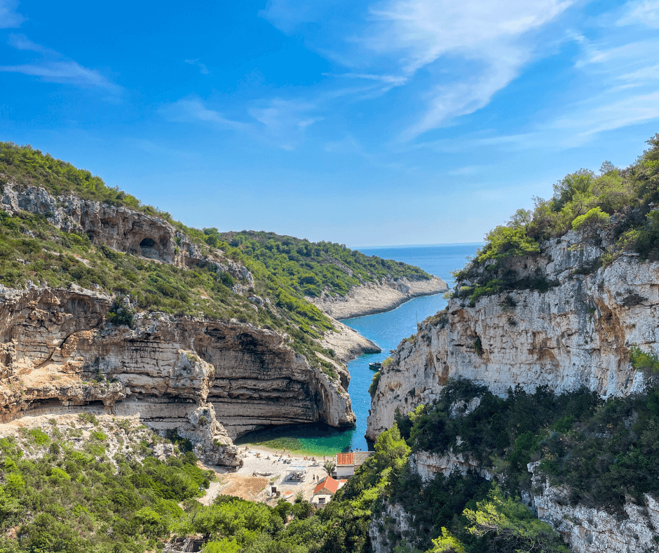 Inselhopping Kroatien - Insel Vis, kleine Bucht inmitten von einer grünbewachsenen Felsenlandschaft, türkisfarbenes Wasser, Meer, Personen liegen am Strand 