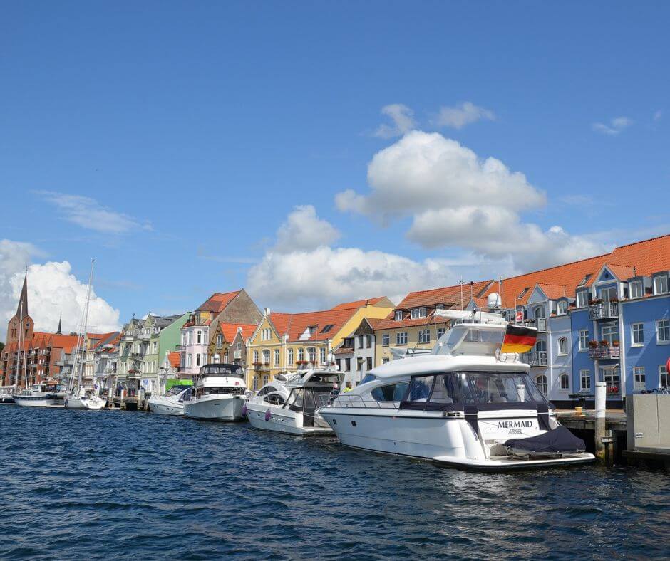 Hafen von Sonderborg. Schiffe sind auf dem Wasser. Bunte Häuser im Hintergrund.