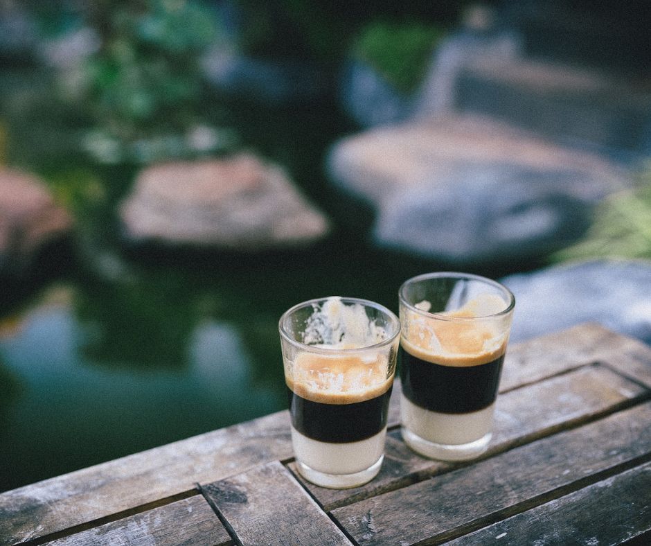 Zwei gefüllte Espressogläser auf einem hölzernen Untergrund.