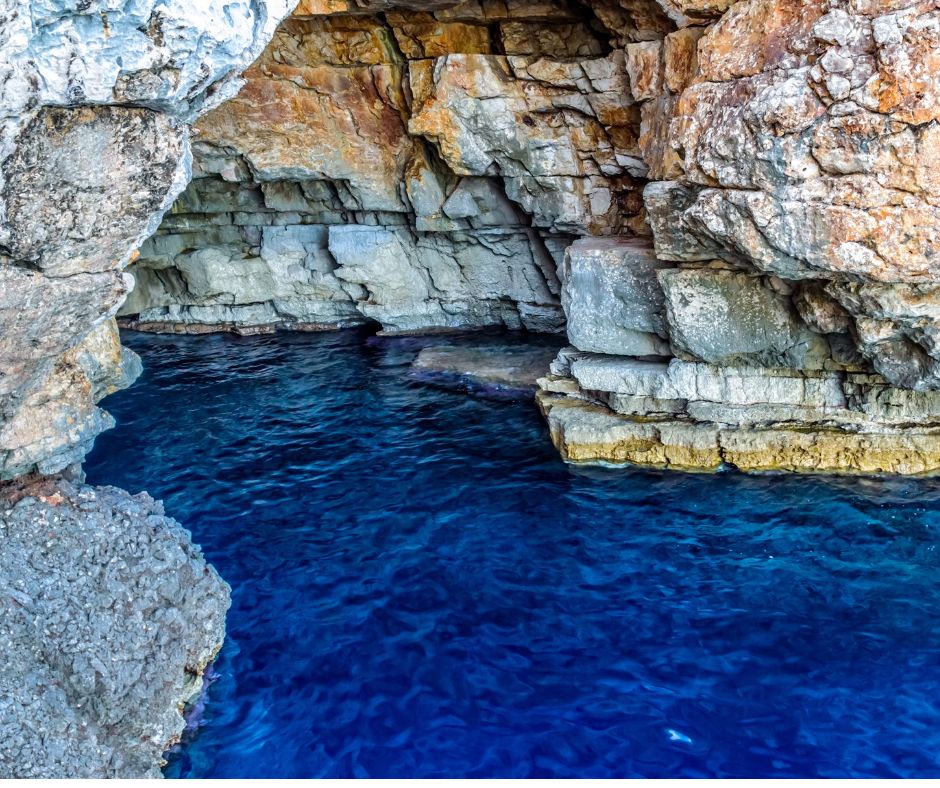 Eingang vom Wasser aus in eine Höhle. Torbogen aus Fels. 