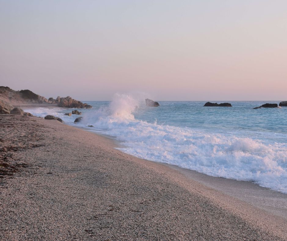 Menschenleerer Strand auf Nisyros in den Abendstunden. Wellen brechen sich am Strand.
