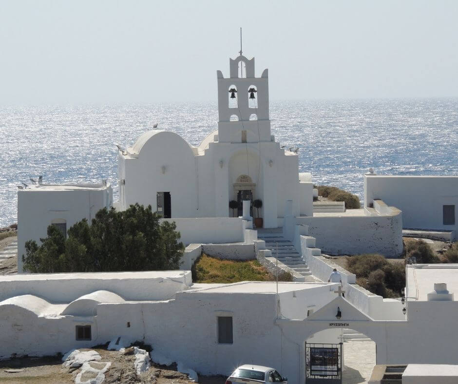 Die weiße Kapelle von Siphnos mit grünen Büschen direkt am Meer.