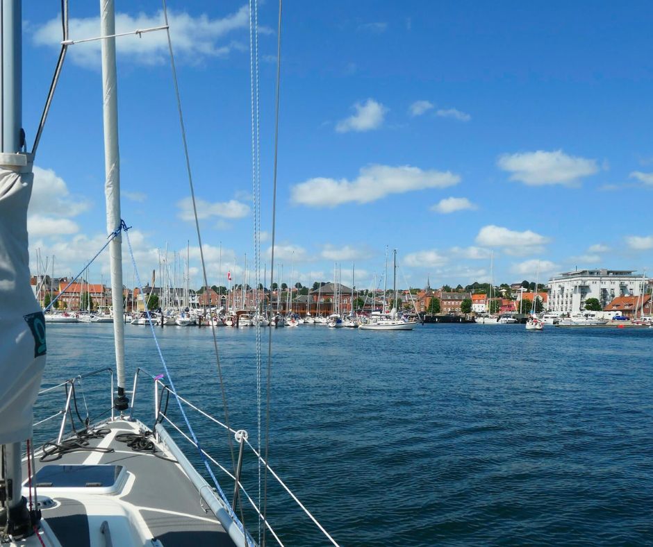 Fotografie von einem Segelboot, welches links im Bild noch zu sehen ist, auf den Hafen und den Ort Svendborg.