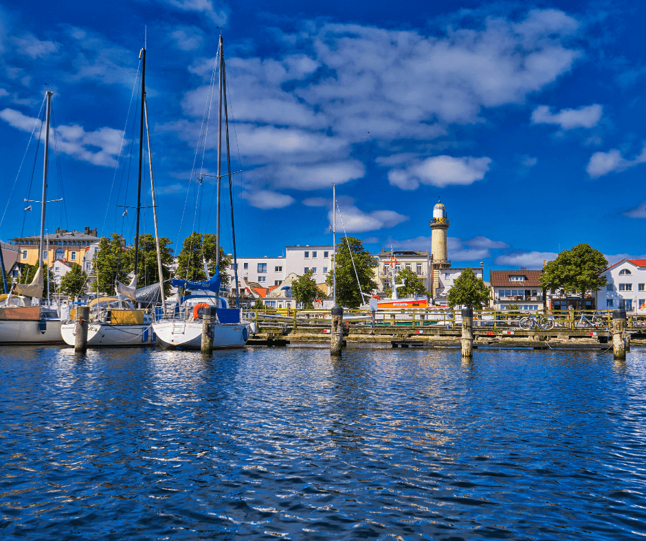 Rostock Hafen mit drei weißen Segelbooten nebeneiander bei klaren blauen Himmel 